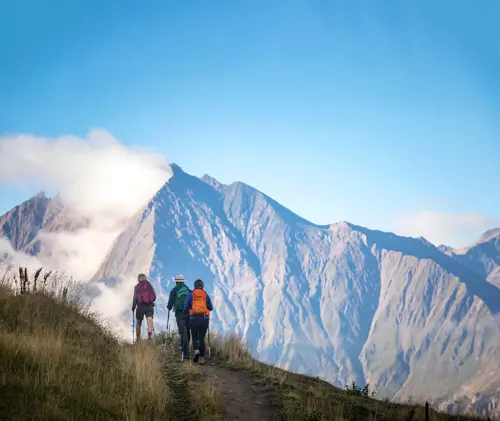 Three people hike the TMB trail with Mont Blanc in the background
