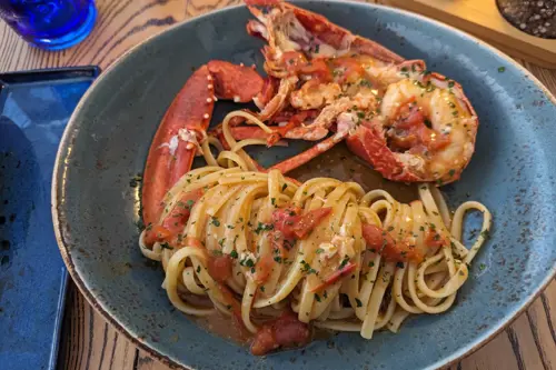 A delicious plate of pasta topped with succulent lobster, elegantly presented on a dining table.