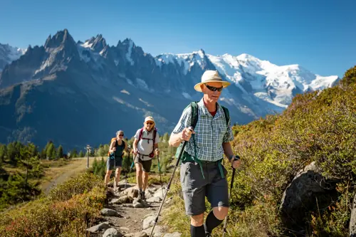 Older man using hiking poles on TMB followed by two females