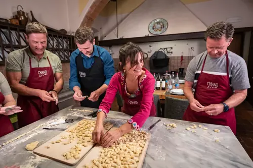 four people wearing aprons learning to make gnocchi