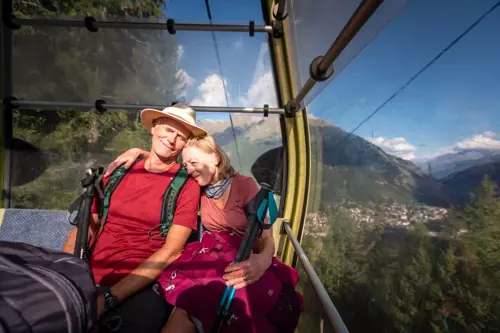 A happy couple enjoying a scenic ride on a cable car, surrounded by stunning mountain views.