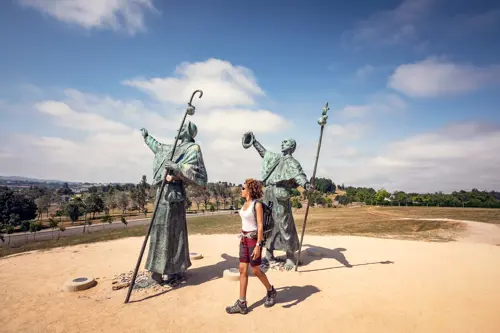 Woman walks between two statues on the Camino de Santiago